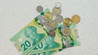 Three twenty dollar bills are on a table with a handful of coinage on top