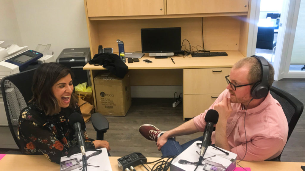 man and woman sit with podcast microphones to record What the Job