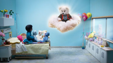 Young Indigenous child sits on a hospital bed and looks up to a floating Spirit Bear