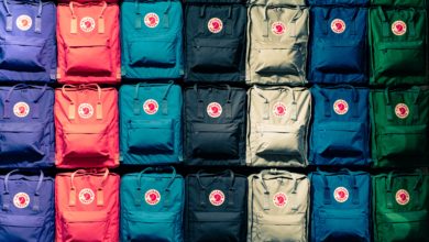 A photo of Fjällräven backpacks on a wall lined up by colour. These are a common type of school bag.