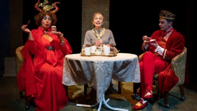 A scene from Fever Land, where Betsy sits between two Fever Land residents.