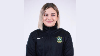 Taylor McPherson poses for a photo against a grey backdrop with her panda's wrestling shirt on.