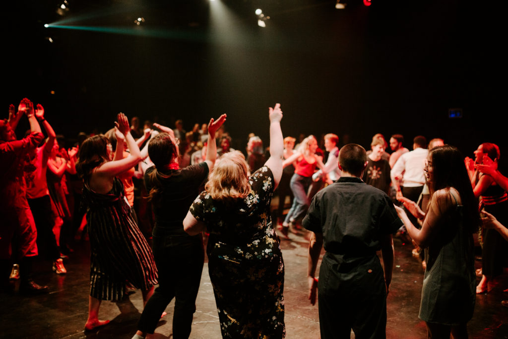 A crowd of people dance in a circle at Nextfest