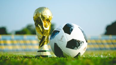 The 2018 FIFA soccer trophy sits next to a soccer ball on a field