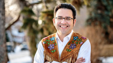 Richard Van Camp poses for a bust-up photo. He is wearing glasses, smiling at the camera.
