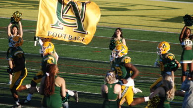 photo of golden bears football players with cheerleaders and flag, photo by Sandra Faul