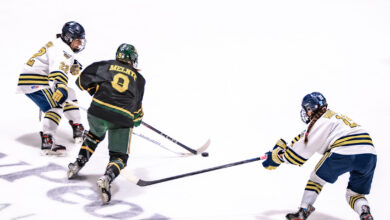 Pandas hockey player Chayse Melnyk splits two NAIT defenders.