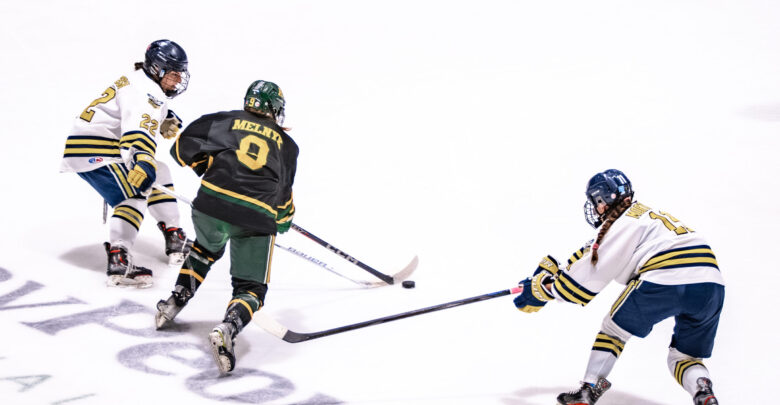 Pandas hockey player Chayse Melnyk splits two NAIT defenders.
